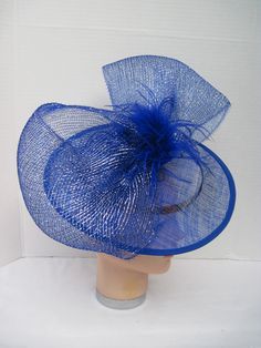 "* Bring in a little excitement to your fashion this season with this bright blue Sinamay hat designed with one gigantic netted bow. Accented with matching Ostrich feathers this is an eye catcher. * The hat is oval with a 2-1/2\" brim and with the clip on the inside can be positioned as desired. The pictures show just two positions as my model has no hair! * This particular design is off the center of the head and can be worn on either the right or left side of the head. * It is light weight, we Blue Brimmed Mini Hats For Party, Spring Party Hat With Ostrich Feathers, Blue Feather Trim Mini Hat For Kentucky Derby, Blue Mini Hat With Feather Trim For Kentucky Derby, Blue Feathered Mini Hat For Summer, Blue Feathered Costume Hats And Headpieces For Spring, Blue Feathered Fascinator For Summer, Spring Costume Hats And Headpieces With Blue Feathers, Blue Feather Fascinator For Summer