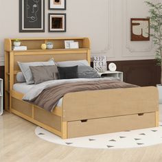 a bed sitting on top of a hard wood floor next to a white wall with pictures above it