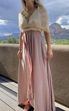 a woman standing on top of a wooden deck wearing a skirt and cropped shirt