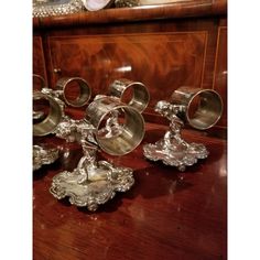 several silver candlesticks sitting on top of a wooden table