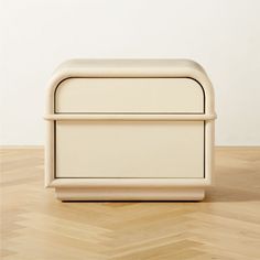 a white box sitting on top of a hard wood floor next to a wall in an empty room