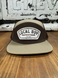 Elevate your outdoor style with the Local Boy Forest Camo Label 7 Panel Hat. This hat combines rugged durability with a touch of modern flair, featuring a classic forest camo pattern in earthy brown and khaki tones. Crafted from high-quality materials, it boasts a 7-panel design that ensures a comfortable, structured fit. The front is adorned with the Local Boy logo on a contrasting label, adding a distinctive touch to your look. The adjustable strap at the back provides a customizable fit for a Casual Khaki Hats For Hiking, Brown Fall Baseball Cap For Outdoor, Casual Hunting Hat With Flat Brim, Khaki Cap For Fall, Fall Hats With Curved Brim For Outdoor Activities, Curved Brim Hats For Fall Outdoor Activities, Casual Flat Brim Hunting Hat, Military Style Brown Baseball Cap With Flat Bill, Khaki Trucker Baseball Cap For Outdoor