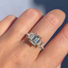 ✦ The Ring Shown in the Picture Holds a Beautiful 1.91 CT Emerald Cut Moissanite. ✦ Main Stone Details✧ Shape: Emerald Cut Moissanite✧ Weight: 1.91 CT (8.50 x 6.50 MM)✧ Color: DEF(Colorless)✧ Clarity: VVS ✦ Side Stone Details✧ Shape: Emerald Cut Moissanite✧ Weight: 1.0 CT (App.)✧ Color: DEF (Colorless)✧ Clarity: VVS ✦ Ring Details ✧ Metal: Gold (10KT, 14KT, 18KT)✧ Metal Tone: Yellow, White, Rose Gold Engagement Rings Sale, Emerald Cut Moissanite, Moissanite Necklace, Types Of Diamonds, Moissanite Earrings, Three Stone Engagement, Moissanite Jewelry, Emerald Engagement, Bridal Bands