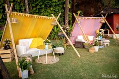 an outdoor seating area is decorated with yellow and pink drapes, white furniture, and potted plants