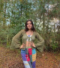 a woman standing in the woods with her hands on her hips and wearing colorful pants