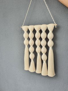 a wall hanging made out of wood beads and tassels on a gray background