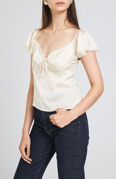 Romantic lace trims the neckline and fluttery sleeves of this slinky satin top that adds sweet, charming style to your next OOTD. 11" center front length (size Medium) Sweetheart neck Short sleeves Partially lined 100% polyester Hand wash, dry flat Imported Fitted Cream Satin Top, Cream Fitted Satin Top, Feminine Satin Top With Lace Trim, Feminine Satin Lace Top, Satin Lace Top For Spring, Spring Satin Top With Lace Trim, Fitted Satin Top With Lace Trim, Fitted Top With Lace Trim And Flutter Sleeves, Fitted Satin Tops With Lace Trim