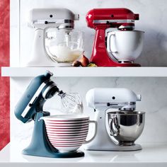 kitchen appliances are lined up on shelves in a row, with one mixer being whisked