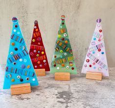 three brightly colored christmas trees on wooden bases