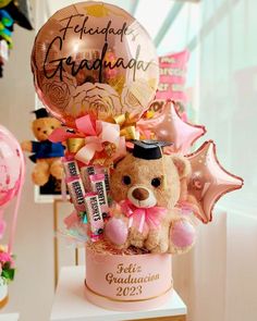 a teddy bear is sitting in a pink cup with balloons and confetti on it