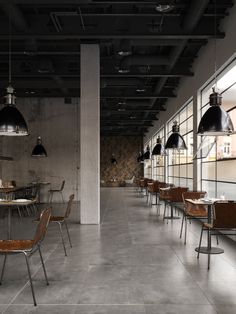 an empty restaurant with tables and chairs in the middle, lights hanging from the ceiling