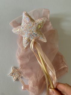 a hand holding a star shaped hair clip in front of a pink tulle skirt