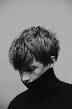 a black and white photo of a man wearing a turtle neck sweater with his hair pulled back