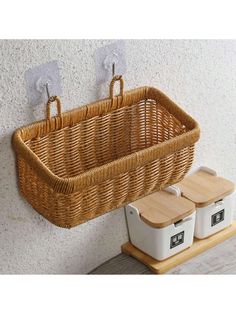 a wicker basket hanging on the wall next to two white storage bins with wooden lids