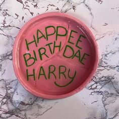 a pink bowl with the words happy birthday harry written on it and green writing in cursive ink