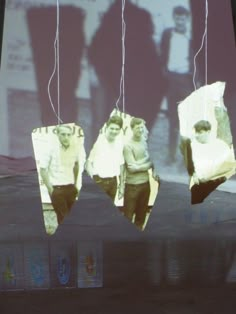 three people hanging from strings in front of a tv screen with the image of them being projected on it