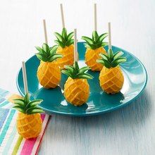 small pineapples are on a blue plate with toothpicks in the middle