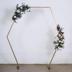 a wooden frame with flowers and greenery on it in front of a white wall