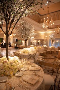 the table is set up for an event with flowers and place settings on it,