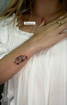 a woman is holding her arm with a small tattoo on it's left arm