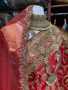 a red and gold bridal gown on display in front of some other clothes racks