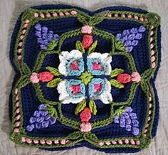 a crocheted square with flowers and leaves on the center is sitting on a bed