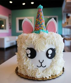 a cake that looks like an alpaca with a unicorn horn on it's head