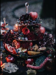 a three tiered tray filled with fruit and flowers