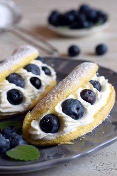 two pastries on a plate with blueberries and powdered sugar in the middle