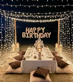 an outdoor birthday party setup with lights and pillows on the ground, along with a sign that says happy birthday