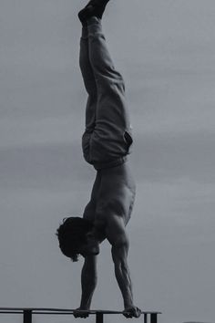 a man doing a handstand on top of a rail