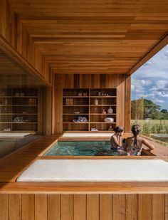 a woman is sitting in the jacuzzi looking out at the water and trees