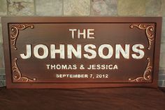 a wooden sign that says the johnsons and is on top of a bed with a brick wall behind it