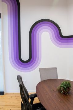 a wooden table sitting in front of a white wall with purple and black lines painted on it