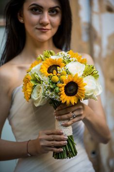 a woman holding a bouquet of sunflowers in her hands