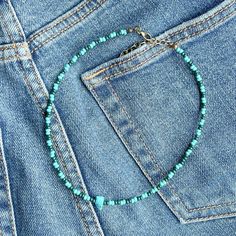 a blue beaded necklace is in the pocket of a pair of jeans