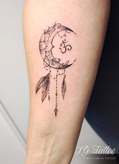 a woman's arm with a tattoo on it that has a moon and feathers