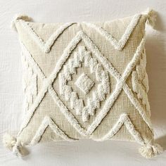 an embroidered pillow with tassels and fringe on the sides, sitting on a white surface