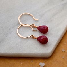 Make a bold but understated statement with our Sookie Earrings. These Ruby earrings feature faceted gems in a crimson red hue. We hand wire-wrap the gemstones in our signature tightrope style, anchored beneath our classic lure earwires. A perfect pop of color! Choose from affordable Gold Fill, Sterling Silver, and Rose Gold Fill; or heirloom-quality solid 14K Gold (Yellow, Rose, or White Gold). Our sustainable jewelry is water resistant - safe for the shower or sea. Details: Gemstone: Ruby Full Dainty Red Earrings For Everyday, Red Drop Earrings For Everyday Wear, Rose Gold Teardrop Ruby Jewelry, Red 14k Gold-filled Gemstone Jewelry, Red 14k Gold Filled Drop Earrings, Dainty Red Jewelry With Ear Wire, Red 14k Gold Filled Earrings For Gift, Minimalist Jewelry Earrings, Drop Earrings Simple