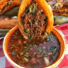 a bowl filled with meat and vegetables on top of a red checkered table cloth