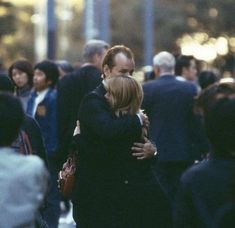 two people hugging each other in the middle of a crowd