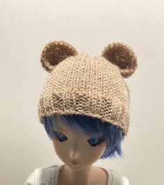 a doll wearing a knitted hat with ears on it's head and blue hair