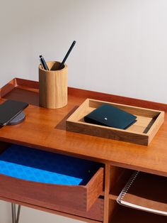 a wooden desk with a pen holder and notebook on it