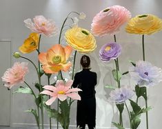 a woman standing in front of a display of paper flowers