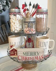 a table topped with mason jars filled with candy and marshmallows next to a sign that says merry christmas