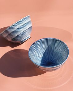 two blue bowls sitting on top of a pink surface