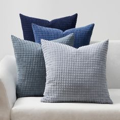 four blue and white pillows sitting on top of a couch