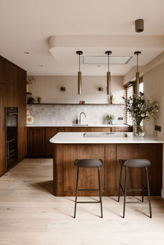 two stools sit in front of an island countertop and sink with wood paneling