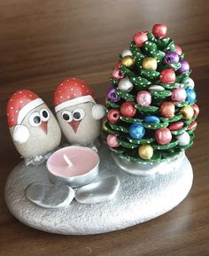 two birds sitting next to each other near a small christmas tree on top of a table