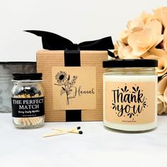 two candles, one with a thank you label and the other with a gift box